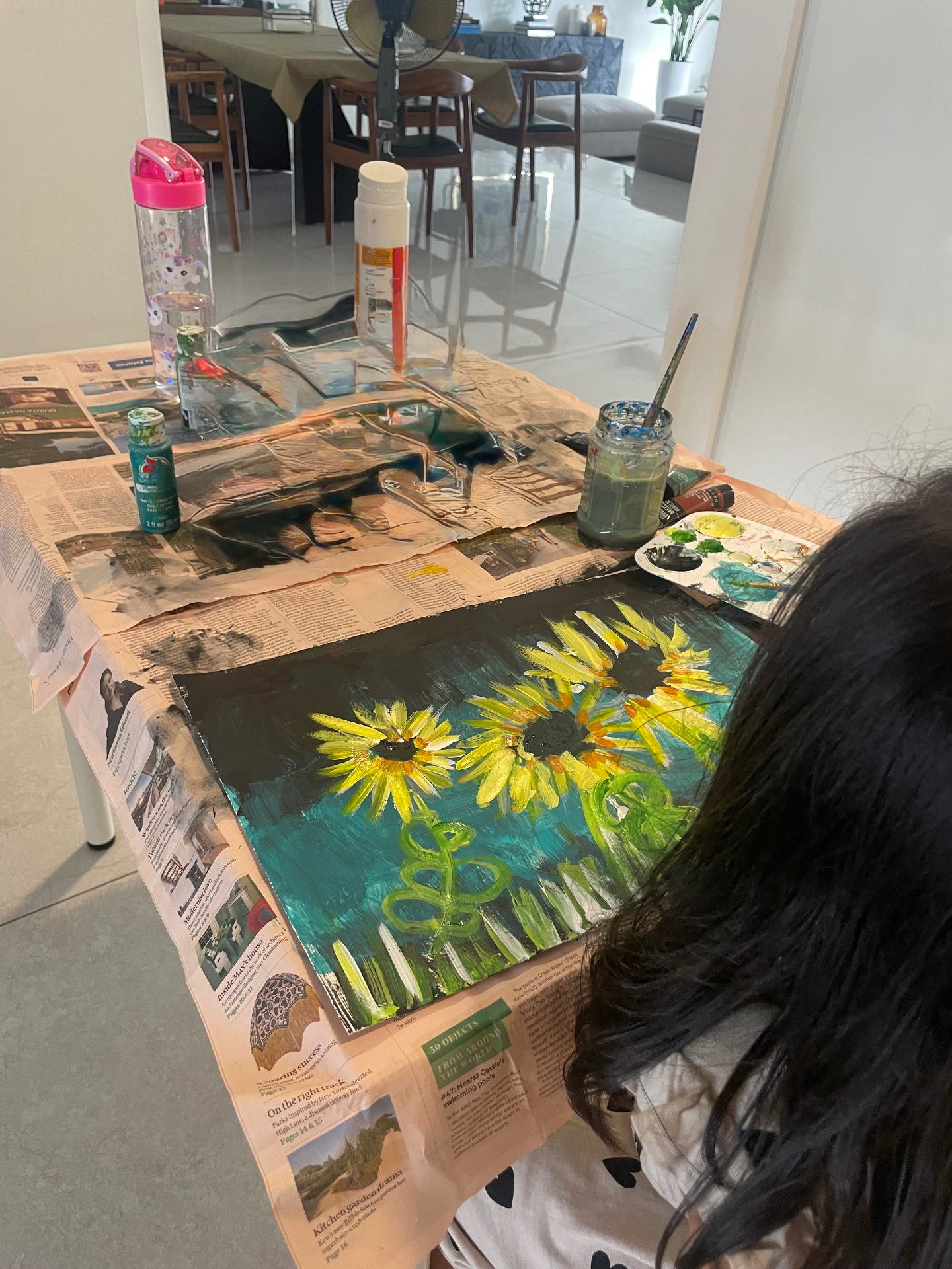 Student painting sunflowers at the studio table