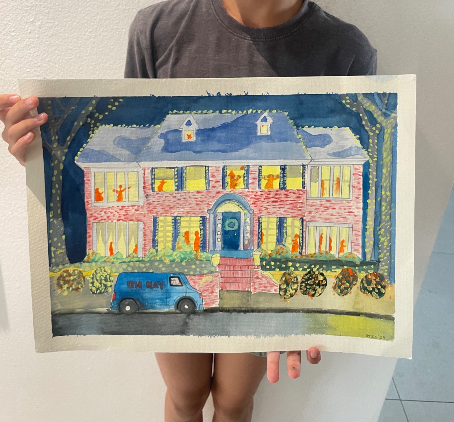 Student holding a watercolor painting of the Home Alone house at night