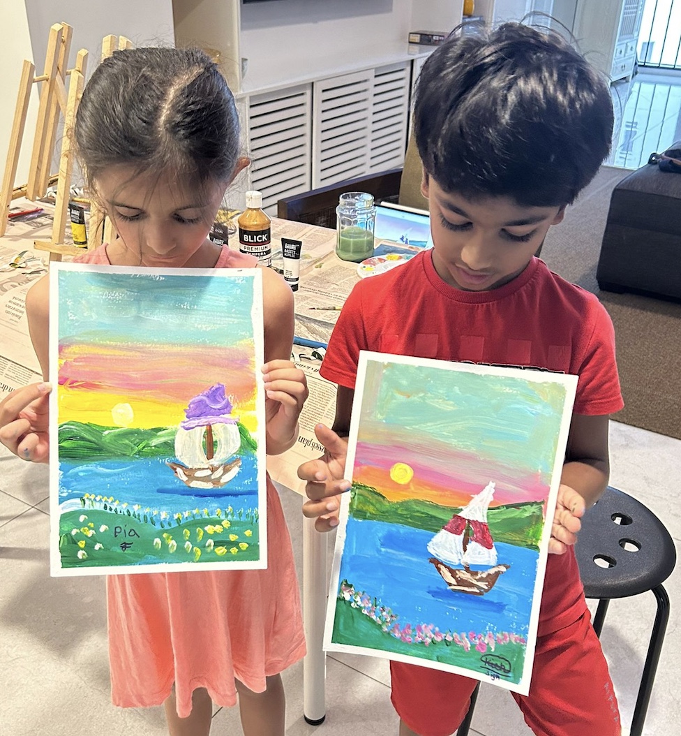 Two young students proudly holding their sailboat paintings