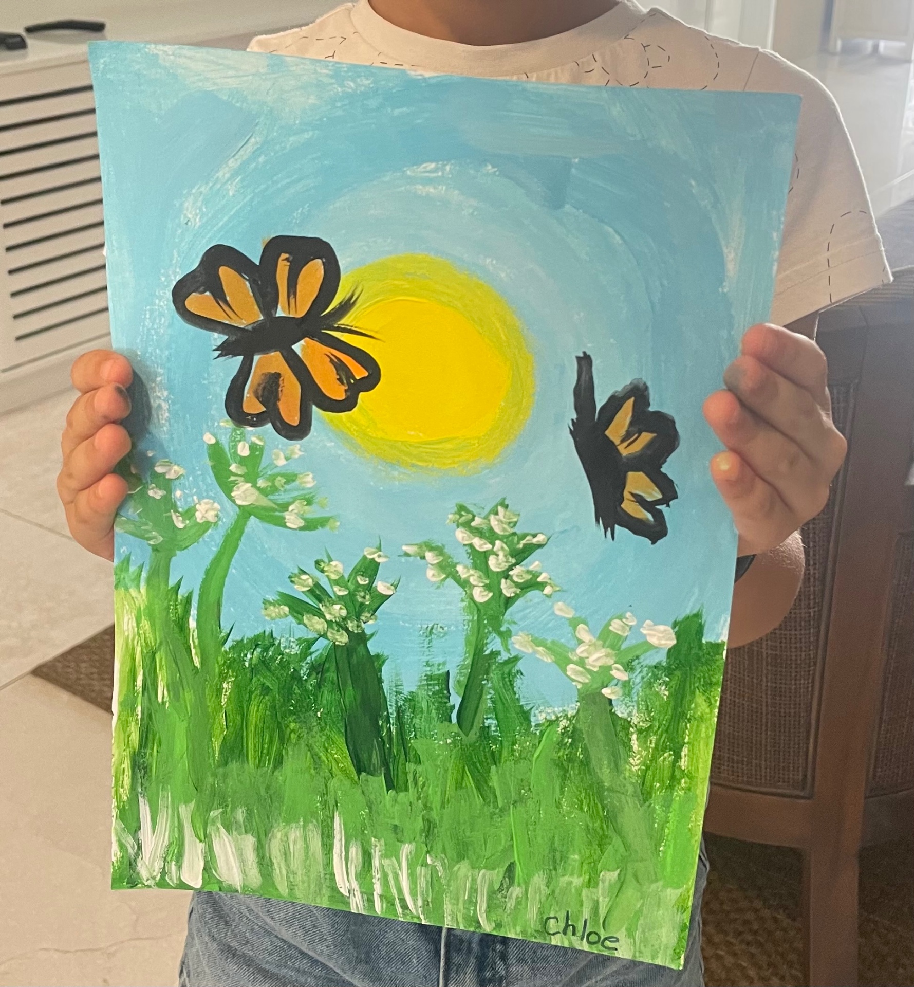Student holding a butterfly and sunshine meadow painting